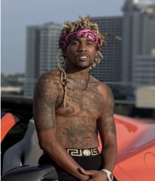 Editor-supplied photograph of Shawty Dred in a pink bandana beside a red-orange vehicle